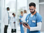Junger Mediziner nutz in einem Krankenhaus ein digitales Tablet.