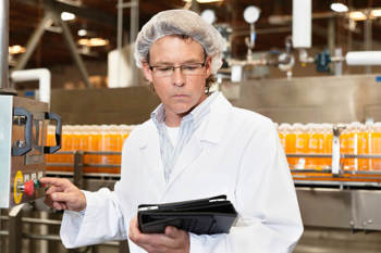 Ein Mitarbeiter in der Lebensmittelindustrie führt an einer Produktionsanlage Kontrollen durch.