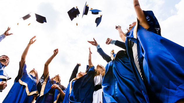 Studienabsolventen werfen ihre Doktorhüte in die Luft.