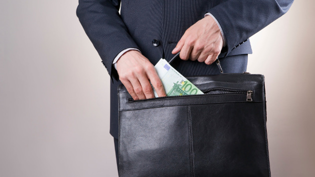 Eine Person in Anzug zieht einen 100-Euro-Schein aus ihrer Aktentasche.