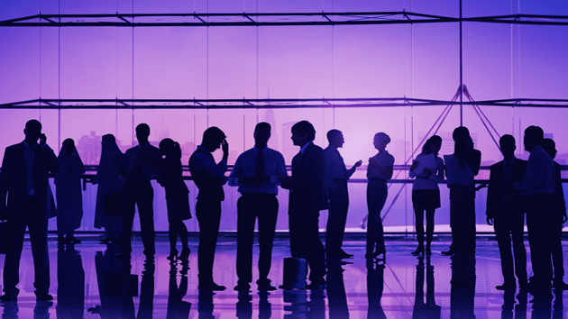 Eine Gruppe von Menschen in Geschäftskleidung sind als Silhouetten vor einem lilanen Hintergrund erkennbar.