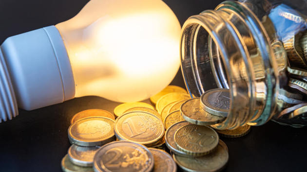 Eine Glühbirne liegt neben einem ausgekippten Geldglas.