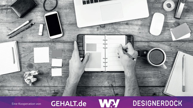 Draufansicht von einem Schreibtisch auf dem ein Terminkalender, ein Smartphone, Stifte und weitere Büroartikel liegen.