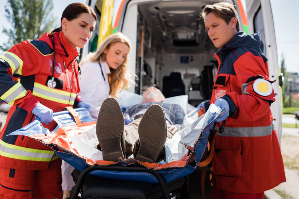 Eine Rettungssanitäterin, ein Notfallsanitäter und eine Notärztin kümmern sich um einen Patienten.