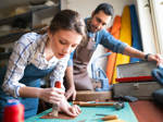 Junge Frau und ihr Mentor arbeiten gemeinsam in einer Lederverarbeitungswerkstatt.