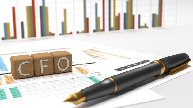 Ein Füller liegt auf Unterlagen mit bunten Statistiken vor Holzwürfeln mit der Aufschrift CFO.