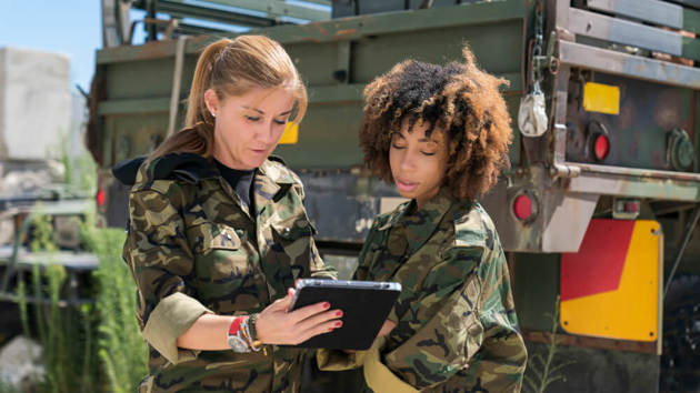 Zwei Soldatinnen schauen auf ein Tablet und reden.