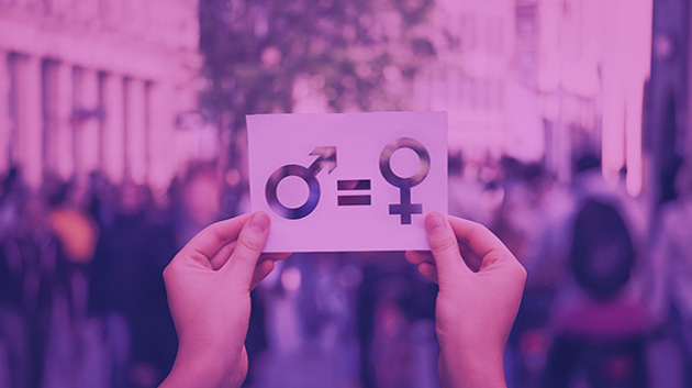 Zwei Hände, die auf einem Blatt Papier das Symbol für Mannlichkeit und Weiblichkeit mit einem Gleichheitszeichen hoch halten.