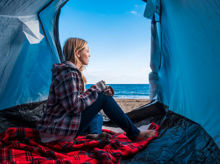 Frau sitzt in einem Zelt an einem Strand