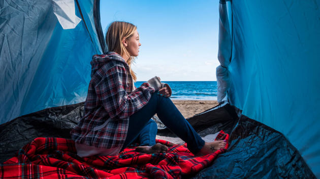 Frau sitzt in einem Zelt an einem Strand