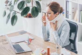 Frau mit Erkältung im Büro
