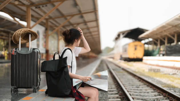 Seitenansicht einer Frau, die auf einem Bahnhof sitzt