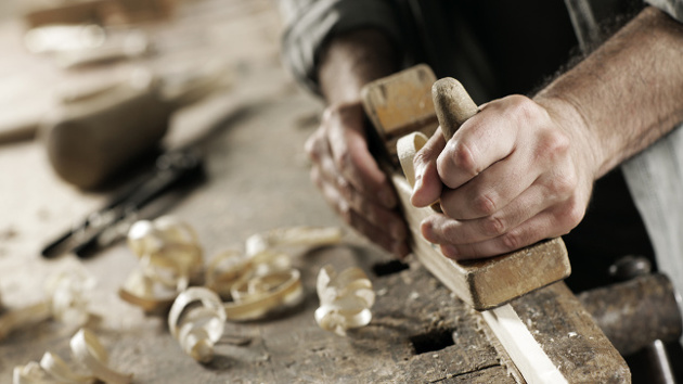 Ein Handwerker bearbeitet Holz mit einem Werkzeug.