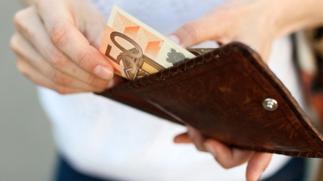 Hände ziehen einen 50-Euro-Schein aus einem Portemonnaie.