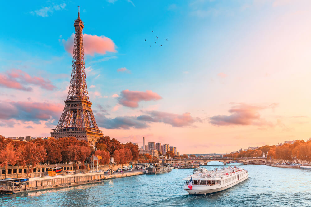 Eiffelturm in den Strahlen der untergehenden Sonne am Ufer der Seine mit Kreuzfahrtschiffen