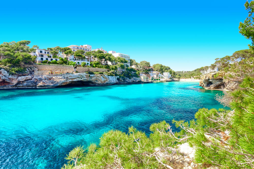 Cala Santanyi-Mallorca-Spanien-Küste. Blaues Meer, Sandküste und weiße Gebäude.