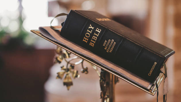 Eine schwarze Bibel liegt auf einer Buchstütze.