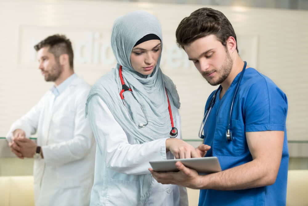 Saudi-arabische Ärztin  und Krankenpfleger bei der Arbeit mit einem Tablet.