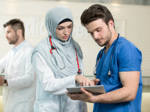 Saudi-arabische Ärztin  und Krankenpfleger bei der Arbeit mit einem Tablet.