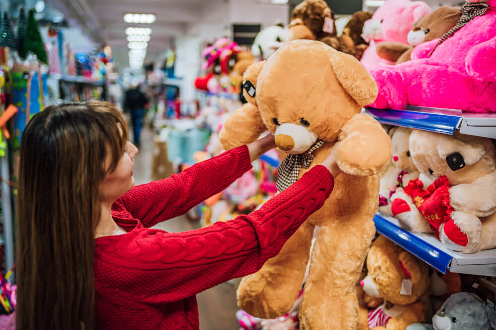Frau wählt Teddybär in einem Spielzeugladen aus