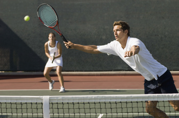 Gemischtes Tennis-Doppel: Der Mann im Vordergrund schnappt der Spielerin im Hintergrund den Ball weg