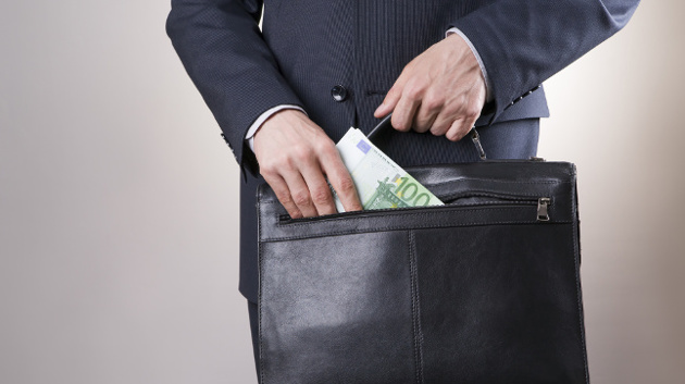 Eine Person in Anzug zieht 100-Euro-Scheine aus ihrer Aktentasche.