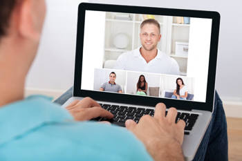 Ein junger Mann nimmt vom Homeoffice aus an einer Videokonferenz mit Kolleginnen und Kollegen teil.
