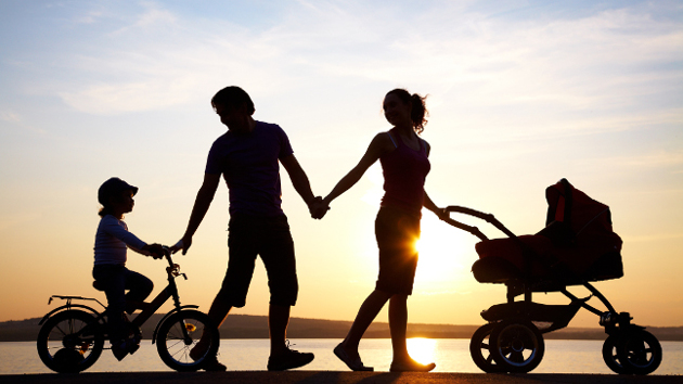Eine junge Familie geht im Sonnenuntergang spazieren. 