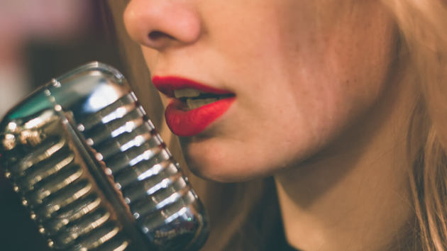 Blonde Frau mit roten Lippen spricht oder singt in ein Mikrofon